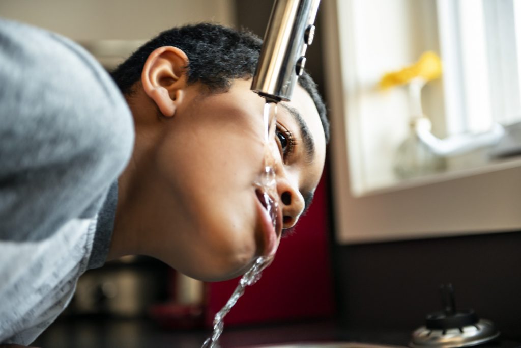 Boy drinking from kitchen tap