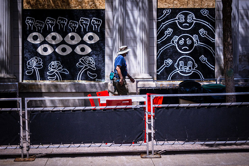 Madison, WI State Street with outdoor tables set up and a man in a mask walking by public art