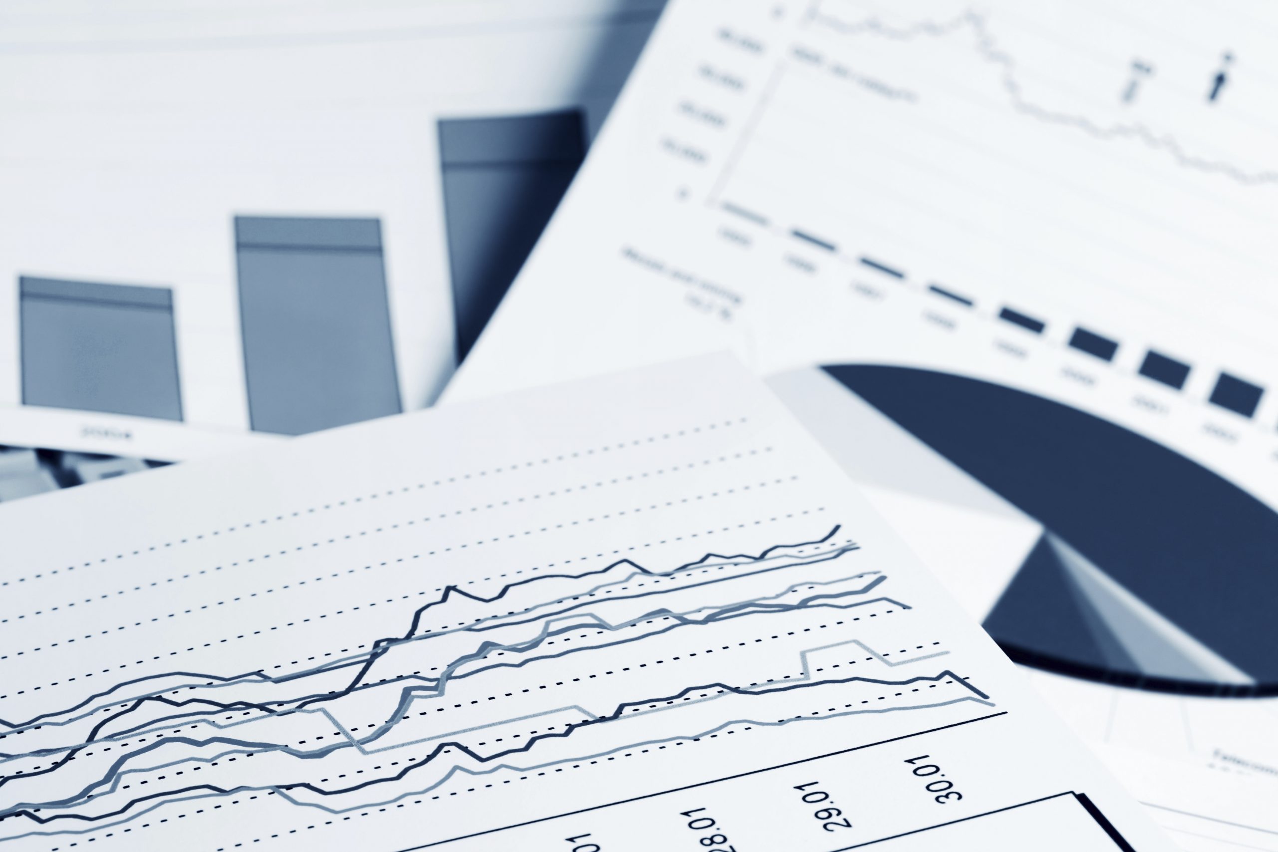 Three sheets of paper with different kinds of charts on them (bar graph, pie chart, and line chart).