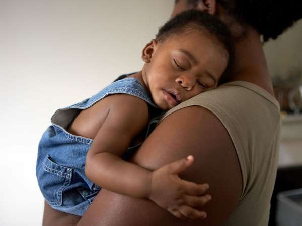 A mother holds a sleeping infant.