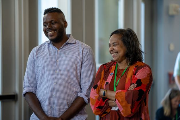 Two conference attendees stand together smiling.