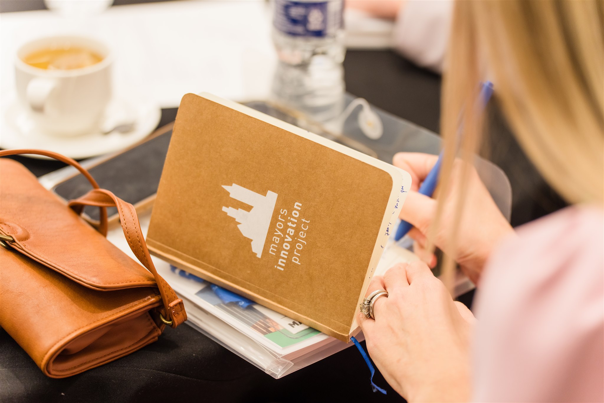 A woman writes in a Mayors Innovation Project notebook.