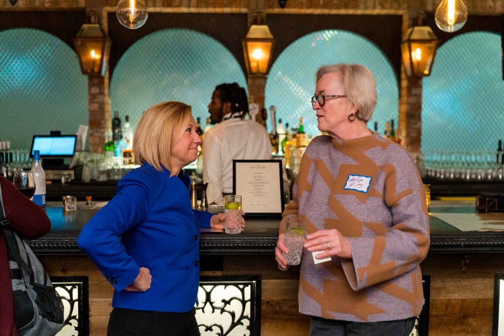 Two women mayors conversing while learning on a counter.