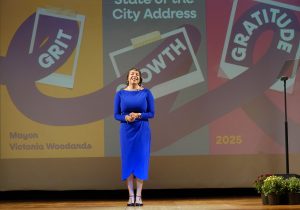 Mayor Victoria Woodards gives her State of the City address standing in the middle of a stage in a blue dress.