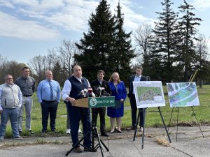Supervisor Brian Kulpa speaks at a podium outside of a park.